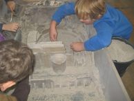 In einem Sandkasten werden echte Ausgrabungsarbeiten durchgeführt.