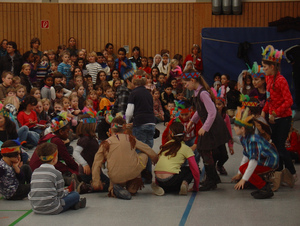 Das Bild zeigt eine Karnevalsfeier der Kinder. Viele Verkleidungen und ein Grupppenspiel.
