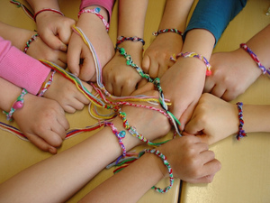 Das Bild zeigt viele Hände von Kindern, die geschmückt sind und sich gegenseitig anfassen.
