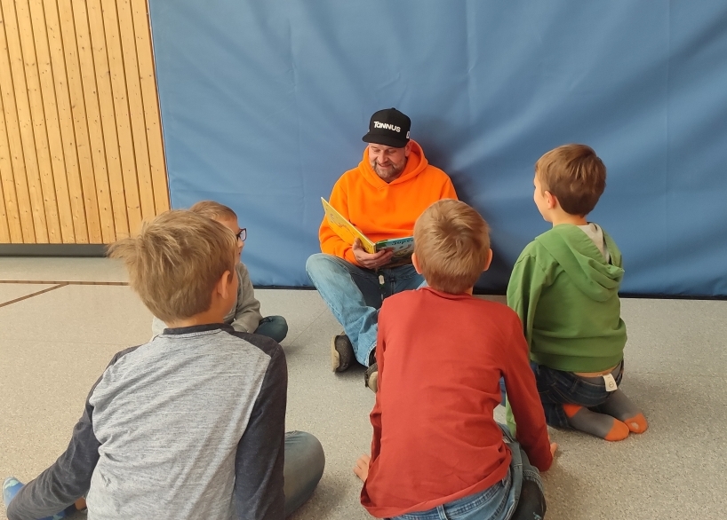 Unser Hausmeister liest Kindern in der Turnhalle vor