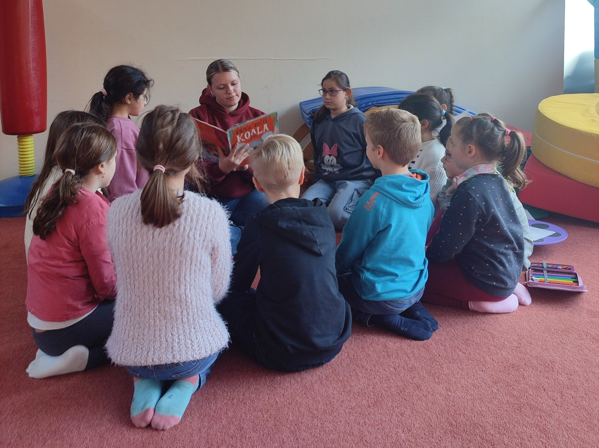 Unsere Mitarbeiterin liest Kindern im Teppichraum vor